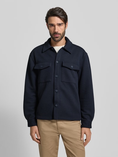 Männermodel trägt Hemdjacke mit Knopfleiste von MCNEAL aus Material-Mix mit Viskose-Anteil, lockerer Schnitt, Kentkragen, Ganzkörperansicht von vorne.