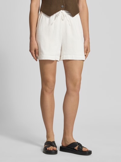 Frauenmodel trägt Comfort Fit Shorts aus reiner Baumwolle Modell 'SASTINA' von Pieces, Optik: Unifarben, Materialverarbeitung: Musselin, mit Tunnelzug, Bundabschluss: Elastisch, seitliche Eingrifftaschen, Farbe Weiß, Nahaufnahme Unterkörper, Ganzkörperansicht von vorne.