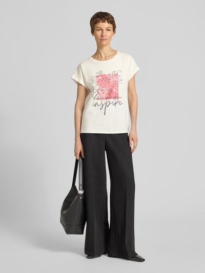 Frauenmodel trägt T-Shirt mit fixiertem Ärmelaufschlag Modell 'RINA' von Soyaconcept, cremefarbener Baumwoll-Mix mit Motiv-Print, Ganzkörperansicht von vorne.