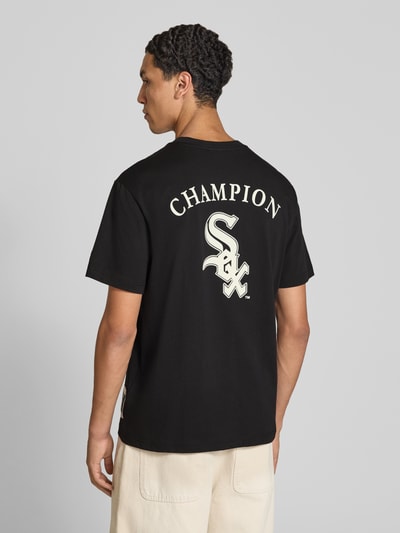 Męski model nosi Relaxed Fit T-Shirt aus reiner Baumwolle od Champion, czarna bawełna, nadruk z napisem, wyhaftowane logo, długość tyłu w rozmiarze M: 70 cm, Ganzkörperansicht Rückansicht
