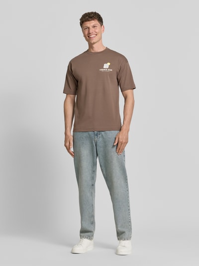 Männermodel trägt T-Shirt mit Motiv-Print und Rundhalsausschnitt von Drykorn, Reine Baumwolle, Regular-Fit, Herren T-Shirt, Ganzkörperansicht von vorne.