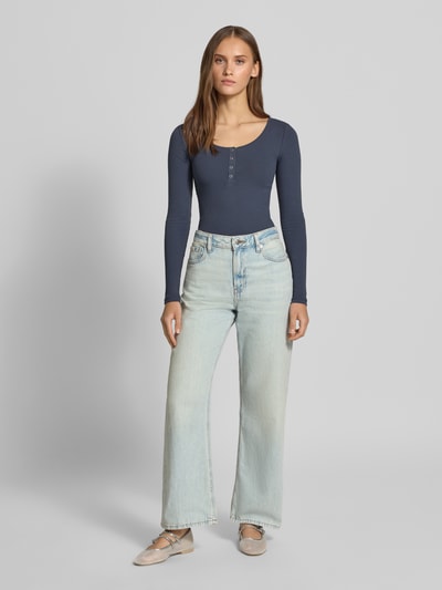 Frauenmodel trägt Slim Fit Langarmshirt aus Baumwoll-Mix Modell 'KITTE' von PIECES, unifarben, Henley-Ausschnitt, Rippstruktur, Ganzkörperansicht von vorne.