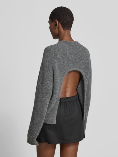 Frauenmodel trägt Pullover in Strick-Optik aus Alpaka-Mix von black palms in Grau, Relaxed-Fit, elastische Ärmelabschlüsse, Rückenlänge bei Größe S 62 cm, offener Rücken, Ganzkörperansicht Rückansicht.