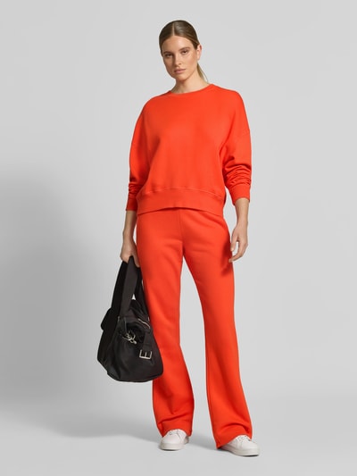 Vrouwenmodel draagt Oversized Sweatshirt aus Baumwoll-Mix van Juvia in feloranje, Mix van katoen en modal, oversized fit, ronde hals, elastische boordjes, ruglengte bij maat S: 54 cm, volledige vooraanzicht.