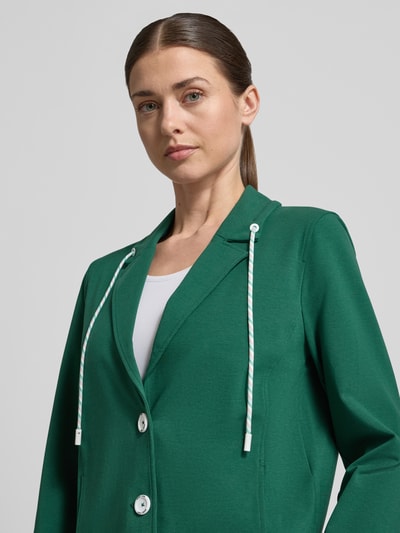Kobieta nosi Regular Fit Blazer mit Eingrifftaschen od Marc Cain, zielony, bawełna-modal z elastanem, zapięcie na guziki, sznurkowy kołnierz, elastyczne mankiety, Szerokość w rozmiarze 36: 49 cm, Długość pleców: 55 cm, Długość rękawa: 63 cm, zbliżenie na górną część ciała z przodu