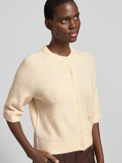 Frauenmodel trägt Cardigan mit Eingrifftasche Modell 'Dathena' von OPUS in hellem Beige, gerader Schnitt, gerippte Abschlüsse, Nahaufnahme Oberkörper.
