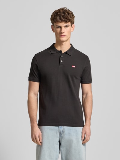 Männermodel trägt Poloshirt mit Label-Detail von Levi's®, Farbe Schwarz, Reine Baumwolle, Regular Fit, Polokragen, Knopfleiste, Ganzkörperansicht von vorne. Rückenlänge bei Größe M: 71 cm.