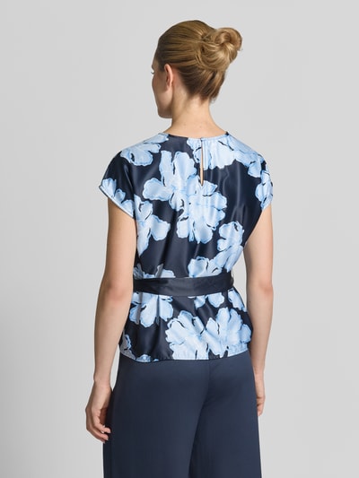 Modelka prezentuje Blusenshirt aus Satin mit Bindegürtel von Christian Berg Cocktail, ciemnoniebieska satyna, wzór na całej powierzchni, taliowany krój, wiązany pasek, okrągły dekolt, długość tyłu w rozmiarze 36: 58 cm, długość rękawów: 13 cm, widok całej sylwetki z tyłu.