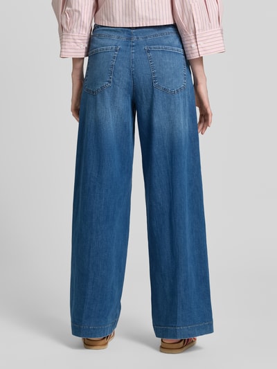 Frauenmodel trägt Wide Leg Jeans mit Bindegürtel Modell 'WENDY' von MAC, mieszanka bawełny i elastanu, szerokość w rozmiarze 36/32: 43 cm, długość wewnętrzna nogawki 82 cm, denim niebieski, widoczne kieszenie, faktura gładka, całkowity widok z tyłu.