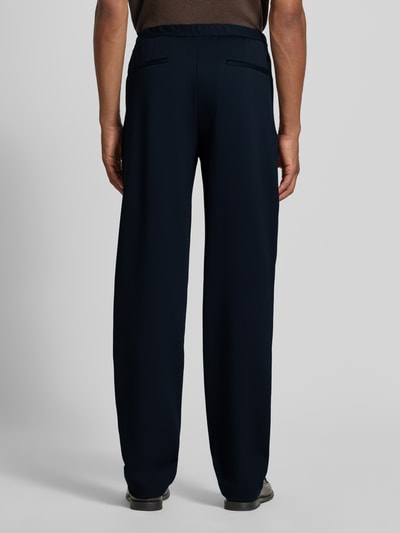 Männermodel trägt Chino mit Gesäßleistentaschen und Eingrifftaschen von Emporio Armani, dunkelblau, Straight Fit, Ganzkörperansicht Rückansicht. Baumwoll-Mix mit Lanawolle-Anteil, Knopf- und Reißverschluss, Bundweite 42 cm, Innenbeinlänge 86 cm.
