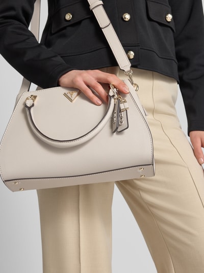 Frauenmodel trägt Handtasche mit Label-Applikation Modell 'NOELLE II' von Guess, cremefarben, strukturierte Oberfläche, Hauptfach mit Reißverschluss, Tragehenkel, Schulterriemen, Maße ca. 32 x 20 x 12 cm, Länge Schulterriemen 119 cm, Nahaufnahme Oberkörper.