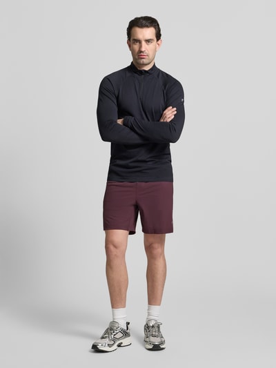Männermodel trägt Regular Fit Shorts mit Logo-Print von Fabletics, bordeauxrot, elastischer Bund, sportlicher Stil, Ganzkörperansicht von vorne.
