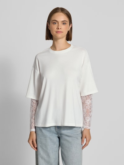 Frauenmodel trägt Regular Fit Langarmshirt mit Viskose-Anteil Modell 'TAHLIA' von ONLY, Damen Langarmshirt, Weiß, gerade Form, glatte und Spitzen-Textur, Ganzkörperansicht von vorne.
