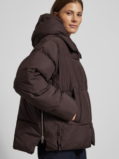 Frauenmodel trägt Steppjacke mit Kapuze und Reißverschluss von Smith and Soul in Dunkelbraun, Regular-Fit, Eingrifftaschen, seitliche Perspektive, Nahaufnahme Oberkörper. Rückenlänge bei Größe S 66 cm, Schulterbreite 42 cm, Brustweite 50 cm, Ärmellänge 68 cm.