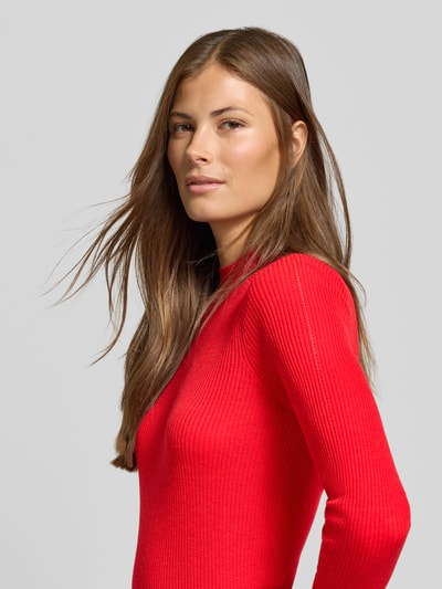 Frauenmodel trägt Slim Fit Pullover mit Woll-Anteil von MYON in Rot mit Stehkragen und Lochmuster, Nahaufnahme Oberkörper.
