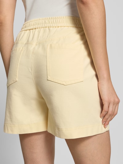 Frauenmodel trägt Shorts mit elastischem Bund Modell 'KATE' von ICHI in hellem Gelb, Baumwoll-Mix mit Stretch-Anteil, Eingrifftaschen, Ganzkörperansicht Rückansicht.
