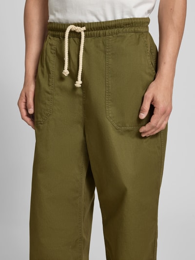 Männermodel trägt Balloon Fit Stoffhose aus Baumwolle von Officine Générale in Olivgrün, Canvas-Optik, Nahaufnahme Oberkörper.