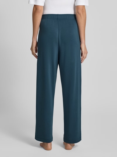 Frauenmodel trägt Sweatpants aus Modal-Mix mit Label-Detail von SCHIESSER in Dunkelblau, lockerer Schnitt, Ganzkörperansicht Rückansicht.