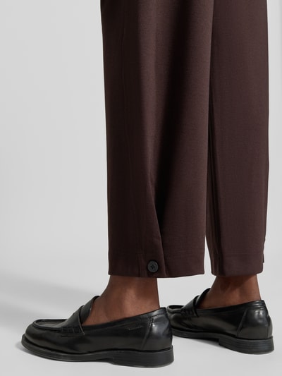 Frauenmodel trägt Wide Fit Hose mit Viskose-Anteil Modell 'Nanni' von FREE/QUENT, dunkelbraun, glatte Textur, Detailaufnahme, Bundfalten und Knopf sichtbar.
