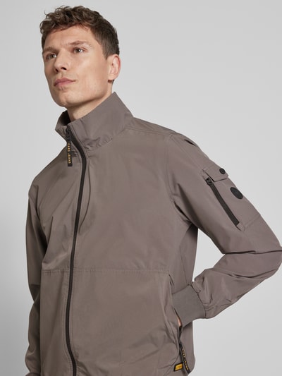 Männermodel trägt windbreaker met materiaalmix met stretch, recht model, opstaande kraag, ritssluiting, ritszak op de mouw, elastische boorden, model 'YETUR' van CARS JEANS, kleur taupegrijs, halfgladde textuur, Nahaufnahme Oberkörper.