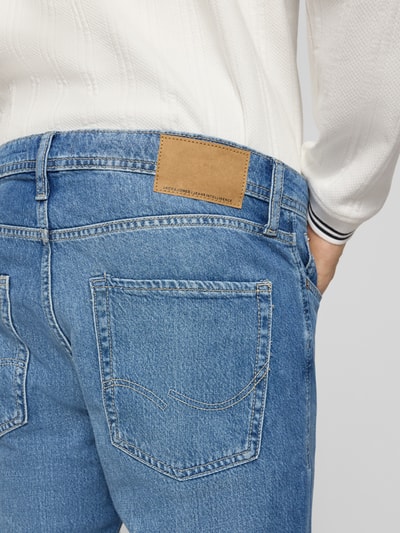 Männermodel trägt Regular Fit Jeans im Used-Look Modell 'CLARK' von Jack & Jones aus reiner Baumwolle, Detailaufnahme Rückansicht, Eingrifftaschen, Bundweite bei Größe 32/34: 45 cm, Innenbeinlänge: 84 cm, blaue Denim-Textur.