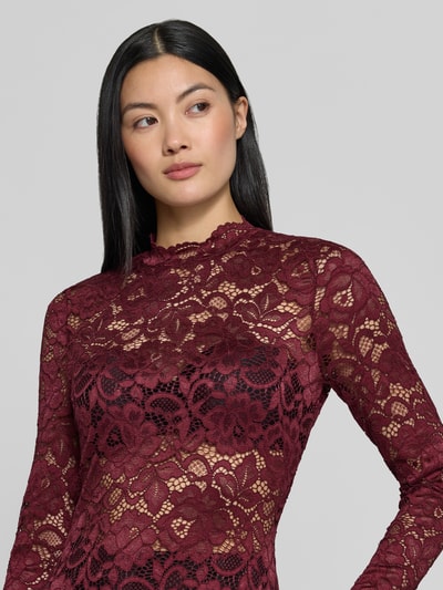 Frauenmodel trägt Slim Fit Longsleeve aus floraler Spitze Modell 'Lacey' von YAS in Bordeaux mit Stehkragen, semitransparentes Design, Nahaufnahme Oberkörper.