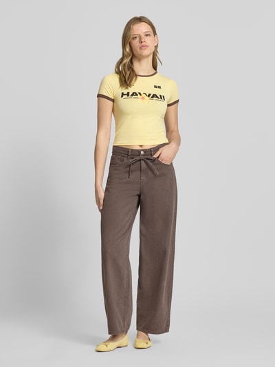 Frauenmodel trägt Slim Fit T-Shirt mit Statement-Print Modell 'Molly' von Noisy May aus elastischem Baumwoll-Mix in Gelb, Rundhalsausschnitt, Ganzkörperansicht von vorne.