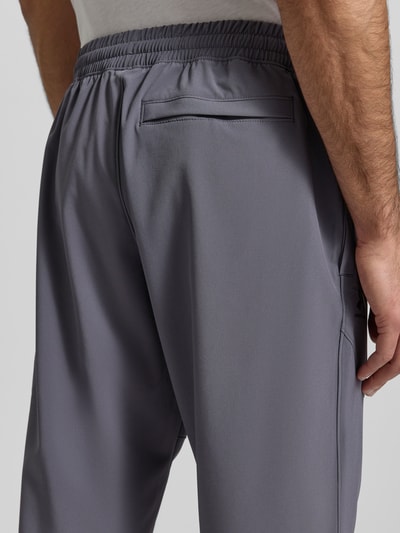 Männermodel trägt Regular Fit Jogger mit Logo-Print Modell 'Vibe' von Under Armour, Elastischer-Material-Mix, Eingrifftaschen, Rückansicht, Detailaufnahme.