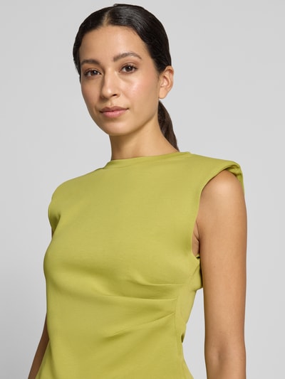 Vrouwenmodel draagt blouse met gelegde plooien Model 'Pina' van YAS in lichtgroen katoenmix, getailleerde pasvorm, mouwloos design, ronde hals, ruglengte bij maat S 54 cm, close-up bovenlichaam.