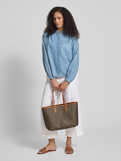 Frauenmodel trägt Shopper mit Logo-Detail Modell 'MONOPLAY LEATHER' von Tommy Hilfiger in Braun mit Allover-Muster, Kunstlederoptik, Ganzkörperansicht von vorne.