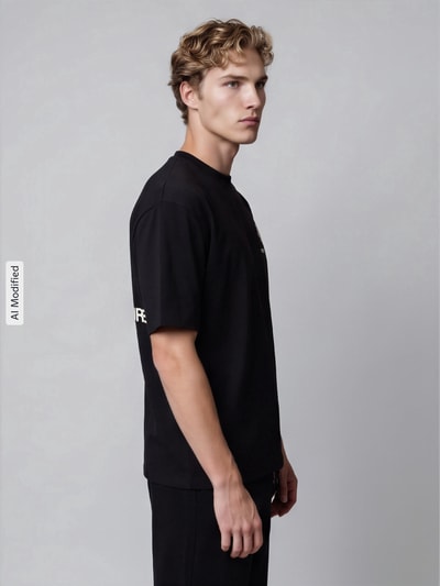 Männermodel trägt zwart boxy fit t-shirt van katoen model 'Azemari' van Don’t Waste Culture, zijaanzicht, KI-modificeerd beeld.