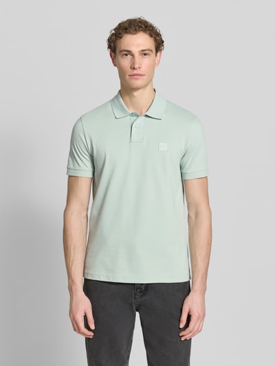 Männermodel trägt Regular Fit Poloshirt aus Baumwoll-Mix Modell 'PASSENGER' von BOSS Orange, Optik: Unifarben, Label-Stitching-Applikation, Polokragen, V-Ausschnitt, kurze Knopfleiste, Ärmelform: Kurzarm, Ärmelabschluss: Gerippt, Materialverarbeitung: Piqué, Ganzkörperansicht von vorne.