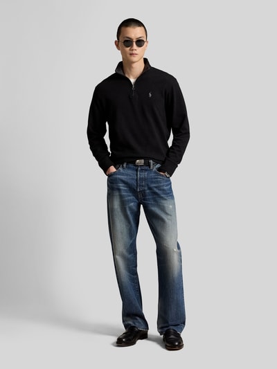 Männermodel trägt Regular Fit Sweatshirt aus Baumwoll-Mix von Polo Ralph Lauren in Schwarz, kombiniert mit Jeans, Ganzkörperansicht von vorne.