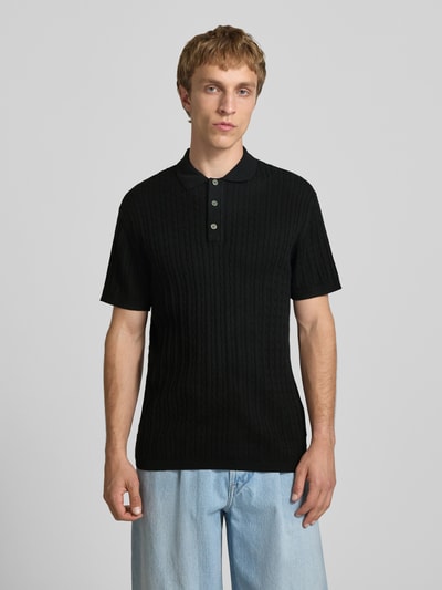 Männermodel trägt Slim Fit Strick-Poloshirt mit Zopfmuster Modell 'EMIL' von Jack & Jones, schwarze Baumwoll-Viskose, Knopfleiste, Ganzkörperansicht von vorne.