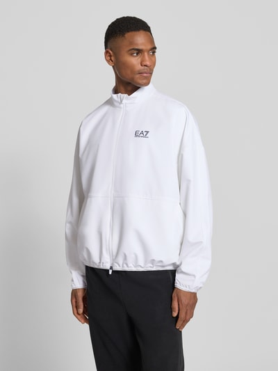 Männermodel trägt Bomberjacke mit Stehkragen und Logo-Print von EA7 Emporio Armani, weiß, glattes VENTUS7-Gewebe, Nahaufnahme Oberkörper.
