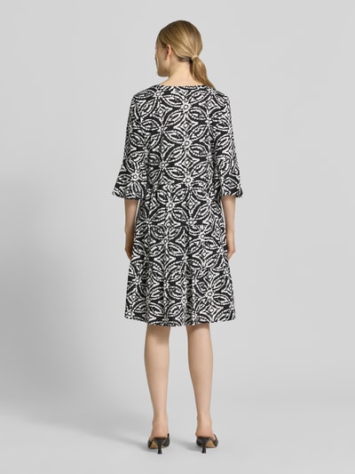 Frauenmodel trägt Minikleid mit Tunika-Ausschnitt von Christian Berg Woman Selection, Schwarz-Weiß-Muster, reine Baumwolle, taillierte Passform, halbarm, Rückansicht Ganzkörperansicht.