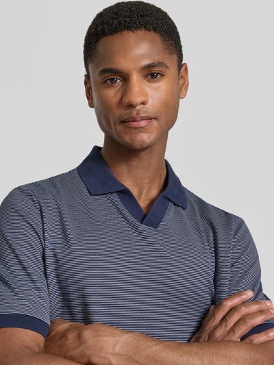 Männermodel trägt Regular Fit Poloshirt aus Baumwolle mit V-Ausschnitt von MAERZ Muenchen, blau gemustert, Label-Detail, Nahaufnahme Oberkörper. Rückenlänge bei Größe 50: 71 cm.