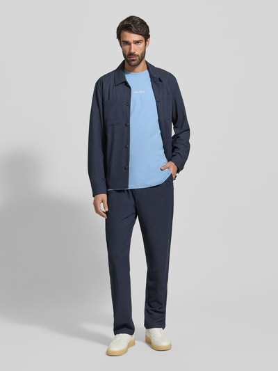 Männermodel trägt Regular Fit Hemdjacke mit Brusttaschen Modell 'Marseille' von Les Deux in Dunkelblau, glatte Textur, Ganzkörperansicht von vorne.