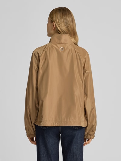 Frauenmodel trägt Jacke mit elastischen Abschlüssen und Stehkragen von Fuchs Schmitt in Braun, Gerader-Schnitt, Raglanärmel, Rückenansicht. Rückenlänge 56 cm, Schulterbreite 38 cm, Brustweite 48 cm, Ärmellänge 43 cm, Seitliche Reißverschlusstaschen, glatte Textur. Ganzkörperansicht Rückansicht.