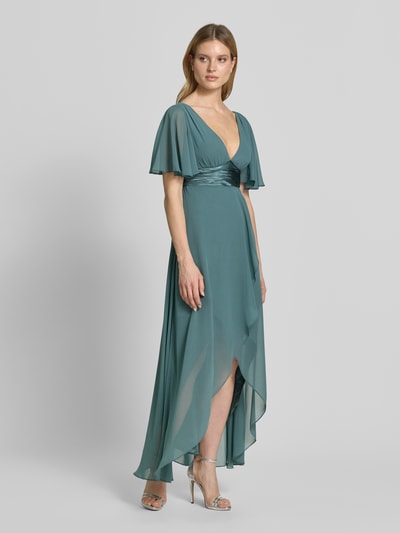 Modelka nosi sukienkę midi z szyfonu z głębokim dekoltem w serek Midikleid aus Chiffon mit tiefem V-Ausschnitt od Jake*s Cocktail, kolor zielony, taliowany fason, falbany, tasiemka w talii, długość tyłu w rozmiarze 36: 125 cm, szerokość w rozmiarze 36: 32 cm, długość rękawów w rozmiarze 36: 30 cm, widok całej sylwetki z przodu.