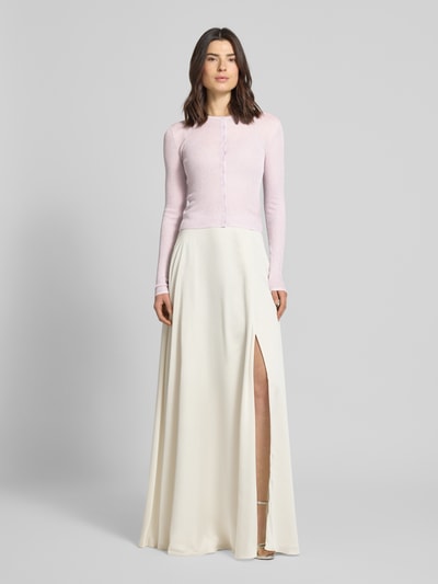 Modelka nosi Kardigan rozpinany z Mieszanki wiskozy od Jake*s Cocktail, krój slim fit, okrągły dekolt, prążkowane wykończenia, długość tyłu w rozmiarze 36: 49 cm, jasnoróżowa góra, jasna długa spódnica, gładka tekstura, cała sylwetka widziana z przodu.