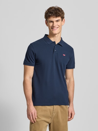 Männermodel trägt Poloshirt mit Label-Detail von Levi's®, navy, Baumwolle, Regular Fit, kurzen Ärmeln, Polokragen, Nahaufnahme Oberkörper.