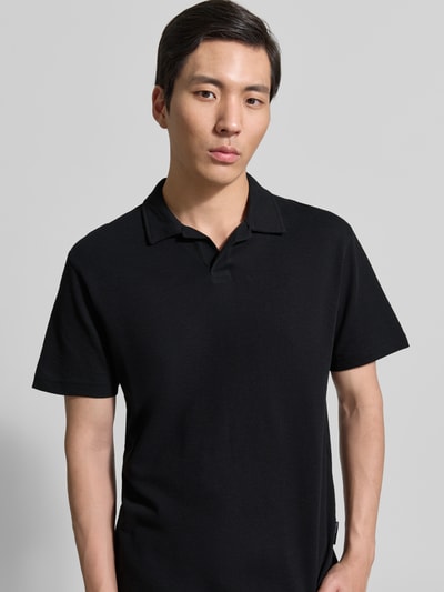 Männermodel trägt Relaxed Fit Poloshirt aus Baumwoll-Mix von Tom Tailor Denim in Schwarz, kurzarm, unifarben, Nahaufnahme Oberkörper.