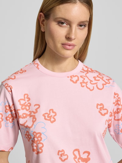 Frauenmodel trägt T-Shirt im Allover-Look mit Rundhalsausschnitt von JAKE*S STUDIO WOMAN, rosa Stoff mit buntem Muster, Nahaufnahme Oberkörper.