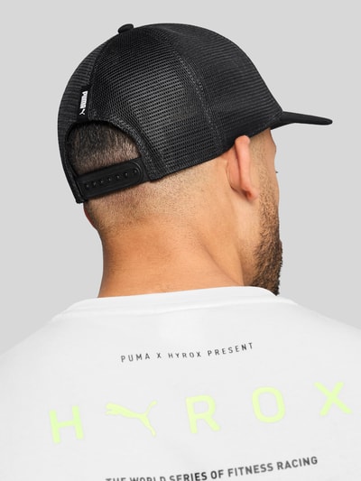 Männermodel trägt schwarze Basecap mit Label-Print von PUMA PERFORMANCE aus reiner Baumwolle, semitransparenter Einsatz, verstellbarer Verschluss, Ganzkörperansicht Rückansicht.