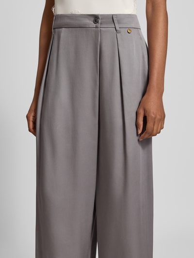 Frauenmodel trägt Wide Fit Hose aus reinem Lyocell von Liu Jo White in Grau, mit asymmetrischem Design und Logo-Detail, Nahaufnahme Oberkörper.