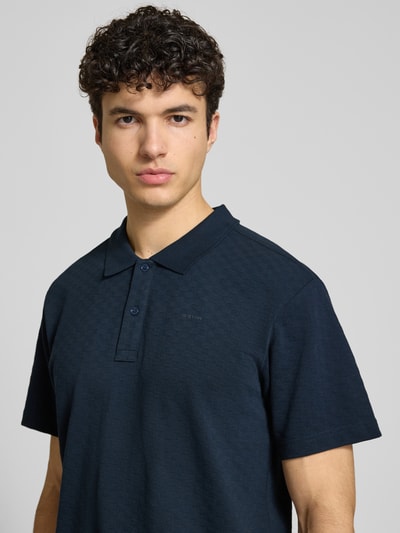 Männermodel trägt Regular Fit Poloshirt mit Logo von G-Star Raw in Dunkelblau, Reine Baumwolle, Knopfleiste, Nahaufnahme Oberkörper. Rückenlänge bei Größe M: 74 cm.