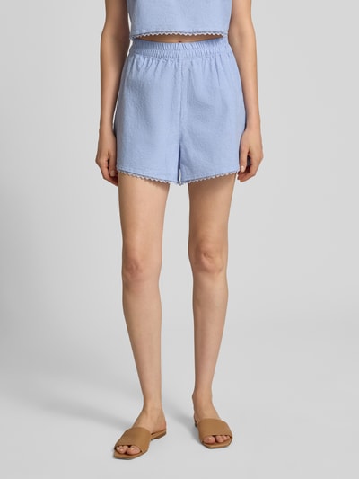 Kobieta nosi Regular Fit Shorts mit Spitzenbesatz Modell 'Feoly' od American Vintage, bawełna, szerokość w rozmiarze S 31 cm, jasnoniebieski, krótkie spodenki, widok z przodu, zbliżenie na dolną część ciała.