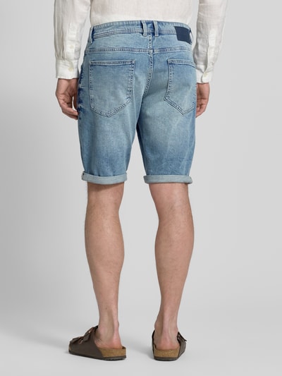 Männermodel trägt Regular Fit Jeans Bermudas aus Baumwoll-Mix von Tom Tailor in blauer Denim-Optik mit Label-Patch, Ganzkörperansicht Rückansicht.