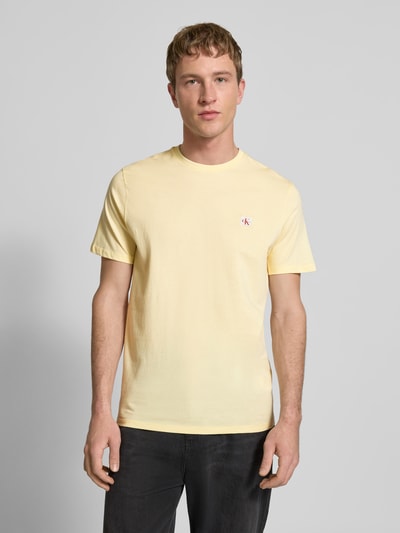 Männermodel trägt T-Shirt mit Label-Badge von Calvin Klein Jeans, Reine Baumwolle, Regular-Fit, Rundhalsausschnitt, Ganzkörperansicht von vorne.